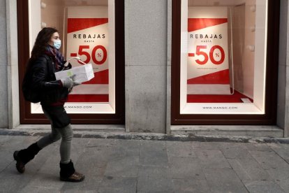 Una mujer pasea por delante un escaparate.