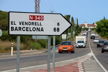 Un rètol de trànsit en primer terme a l'N-340 a Roda de Berà, amb els quilòmetres que separen Roda de Berà del Vendrell i Barcelona.