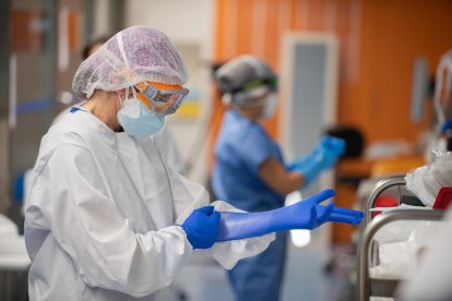 Una sanitaria del Clínic poniéndose guantes de protección en la UCI con enfermos de covid.