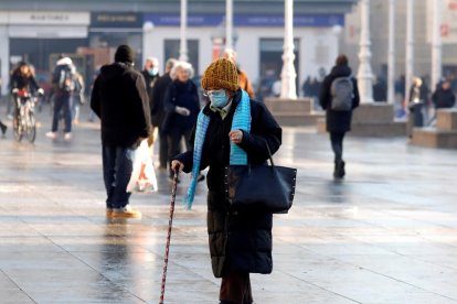 Una mujer andando con mascarilla.