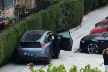 Un dels agents inspeccionant el vehicle abandonat a la vorera.