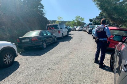 Un mosso ante hileras de coches mal aparcados en arcenes de la carretera durante las vacaciones de Semana Santa a Tarragona.