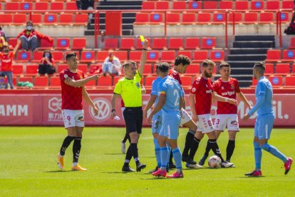 El colegiado del Nàstic-Ibiza muestra una tarjeta durante el partido de ida en el Nou Estadi, que acabó con triunfo visitante (0-1).