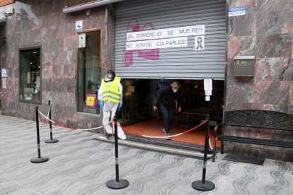 Una comerciante saliente de una tienda de Cambrils que está levantando la persiana para protestar contra el cierre de los establecimientos los fines de semana.