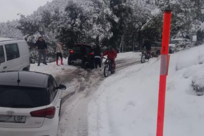 Vehicles fora de la via a l'accés a Prades des d'una màquina llevaneu de la Diputació.