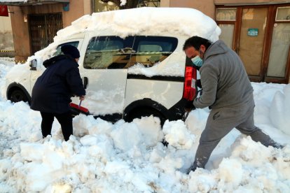 Dos vecinos de Falset desenterrando su vehículo, enterrado por la nieve.