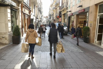 Ciudadanos con bolsas por el carrer de Monterols.