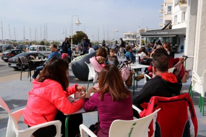 Personas consumiendo en una terraza de un bar de la zona marítima de l'Ampolla esta Semana Santa.