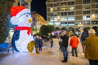 Dos niñas se fotografían con el pingüino de la plaza Prim, ayer.