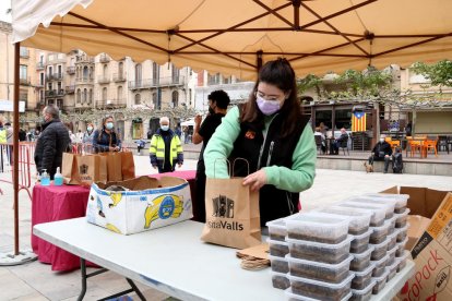 Una noia preparant racions de faves a la plaça del Pati de Valls, un dels punts habilitats de recollida de la 3a edició de la Favatada.