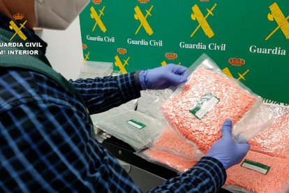 Imagen policial de un agente de la Guardia Civil interviniendo varios paquetes con pastillas de MDMA encontrados entre el equipaje de un conductor.