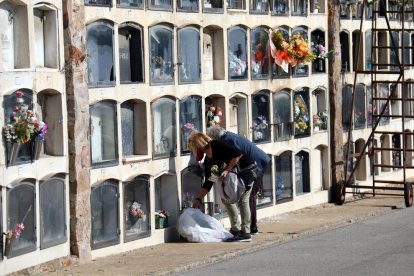 Dues dones dipositen flors en una tomba al cementiri de Montjuïc per Tots Sants