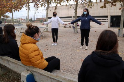 Pla mitjà d'un grup de joves seguint les indicacions i recomanacions anticovid de dues alumnes de l'Institut d'Alcanar.