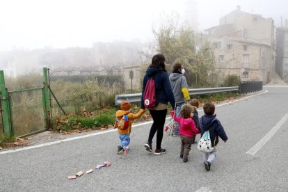 L'educadora i els infants de l'espai familiar d'autogestionat de La Muntanya d'Arbolí caminat pel poble d'esquenes.