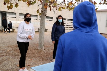 Un jove amb caputxa conversant sobre les mesures anticovid amb dues companyes de l'institut a Alcanar.