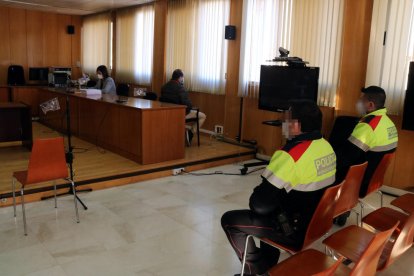 Plan|Plano abierto del hombre condenado por abusos sexuales a menores, sentado en la sala de vistas de la Audiencia de Tarragona, con dos agentes de los Mossos d'Esquadra en primer término