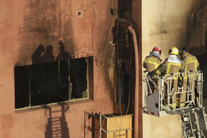 Els Bombers inspeccionen l'interior de la nau cremada.