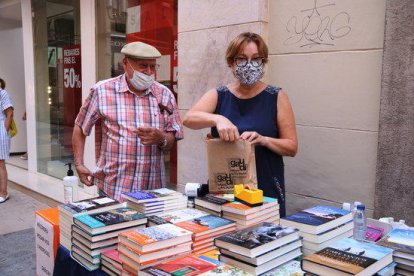 Un client comprant un llibre en la parada de la llibreria Gaudí de Reus en el Sant Jordi d'estiu.