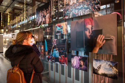 Una noia observa algunes de les fotografies que s'exposen al Mercat Central