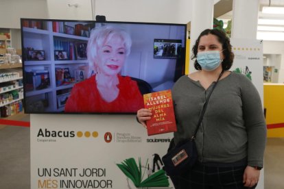 Una chica se fotografía con Isabel Allende (presente virtualmente) después de recibir una firma telemática de la autora chilena.