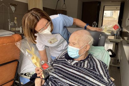 Un anciano de un geriátrico recibiendo una palma, en el marco de una campaña solidaria de un taller artesano de la Vilella Baixa.