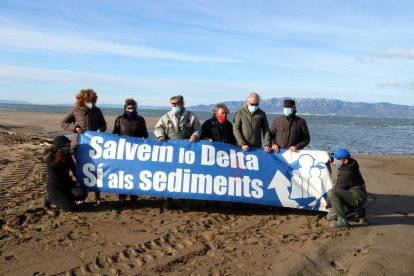 Activistas de l'Associació Sediments con una pancarta reivindicativa antes de comenzar la acción visual para denunciar la fragilidad de la barra del Trabucador.