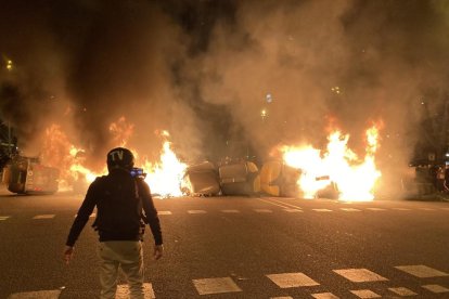 Un manifestant davant d'una barricada de contenidors encesa en la quarta nit de protestes per l'empresonament de Pablo Hasel.