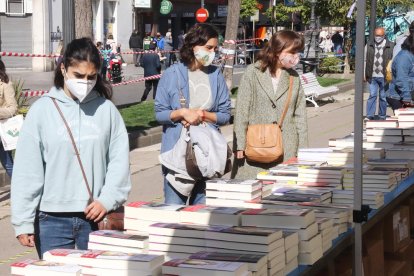 Una noia mirant llibres en una parada de la Rambla Nova de Tarragona durant la Diada de Sant Jordi.