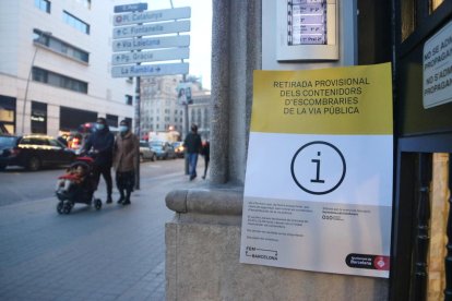 Un cartel a la puerta de un bloque de pisos de Barcelona avisa que se han retirado los contenedores de la calle por precaución.