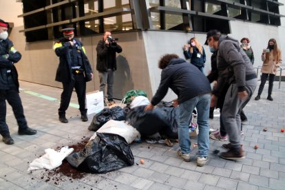 Alguns restauradors llençant bosses de brossa davant del cordó policial a les portes de la seu del Govern.