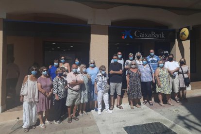 Imagen de la veintena de vecinos protestando delante de la sucursal de CaixaBank.