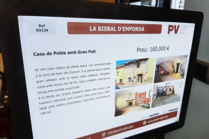 Un cartel de una casa en venta en una inmobiliaria de la Bisbal d'Empordà.