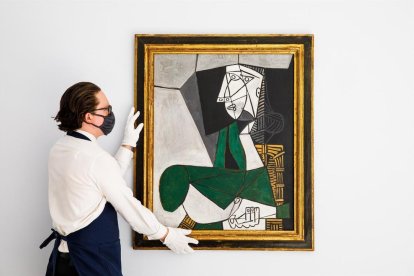 Fotografía cedida por Sotheby's de uno de sus empleados mientras cuelga la obra 'Femme assise en costume vert'.