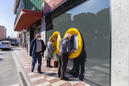 Imatge de dos veïns del barri de Sant Pere i Sant Pau de Tarragona fent gestions al caixer.