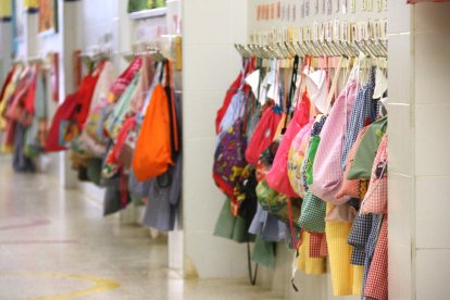 Un passadís de l'escola Cèsar August de Tarragona, buit d'alumnes, amb els penjadors carregats amb bates i motxilles dels petits.