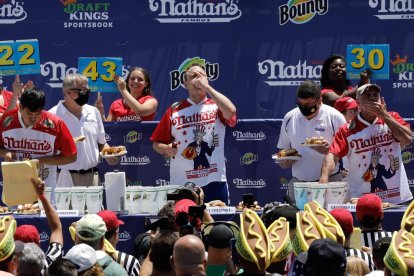 Joey Chestnut al centre de la imatge competint amb dos rivals més.