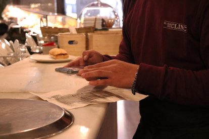 Pla curt de la mà d'un cambrer demanant el certificat covid a l'entrada d'un bar.