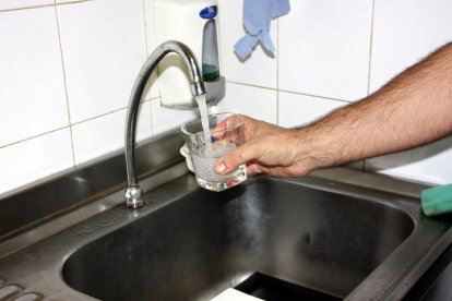 Imagen de archivo de una mano llenando un vaso de agua al grifo.