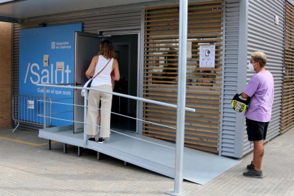 Dos personas esperando para acceder a un centro sanitario para hacerse pruebas PCR.