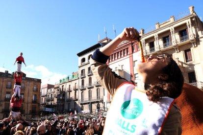 Imatge d'arxiu d'una de les concursants del Concurs de Menjar Calçots amb els pilars de les colles castelleres vallenques en la Gran Festa de la Calçotada.