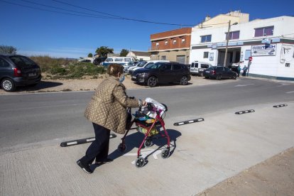 Imagen de una señora pasando por la nueva acera con un carro.