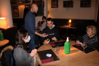 Un restaurador comprovando el pasaporte covid en un bar de Gracia.