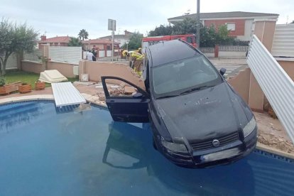 Imagen del vehículo que ha tenido que ser asegurado por los bomberos para que no cayera a la piscina.