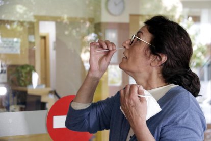 Una mujer haciéndose un frotis nasal para la PCR.