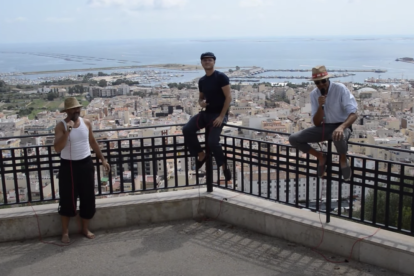 Imagen del videoclip con el tres músicos y el municipio en el fondo.