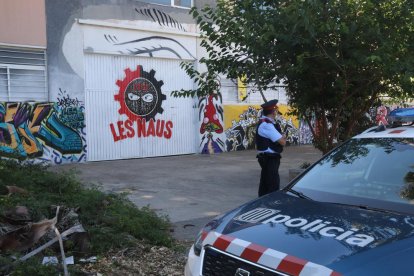 Plano general de la puerta principal del CSOA Les Naus de Torredembarra, vigilada por un agente de los Mossos d'Esquadra.