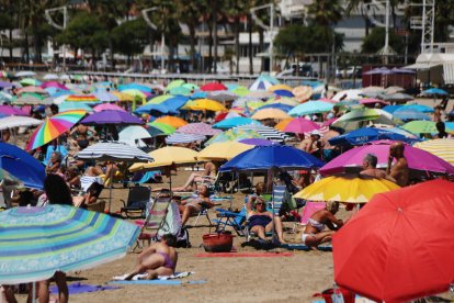 Pla obert d'una platja de Cambrils (Baix Camp) plena de para-sols. Imatge del 27 de juliol de 2021