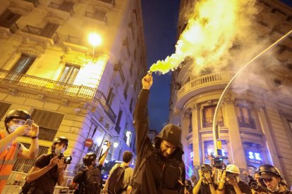 Un hombre con capucha sujeta una bengala en la vía Laietana de Barcelona el 11 de septiembre del 2021.