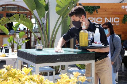 Un cambrer d'un restaurant de Sitges netejant la taula entre serveis d'aperitius.