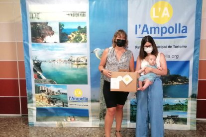 La regidora de Medi Ambient de l'Ampolla, Meritxell Faiges, fent entrega del lot de productes ecològics a una mare i el seu nadó.